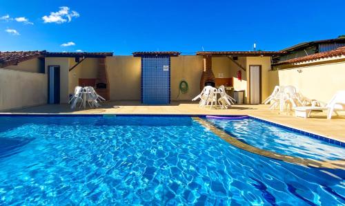 una piscina con sillas blancas en un patio en Residencial Malibu, en Porto Seguro