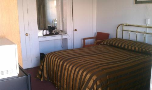 a hotel room with a bed with a striped blanket at San Joaquin Motel in Merced