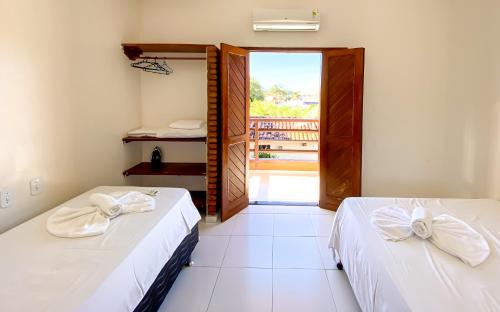 duas camas num quarto com uma porta para uma varanda em Residencial Malibu em Porto Seguro