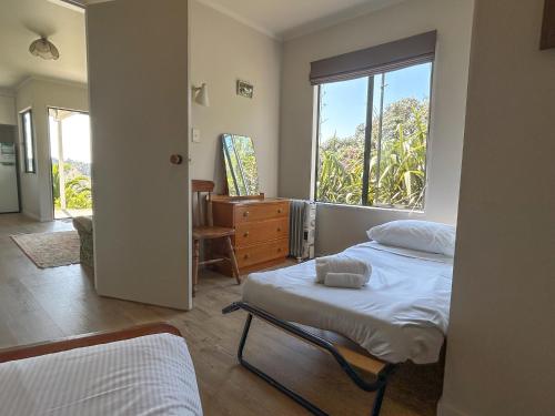 a bedroom with two beds and a window at Chenies Holiday Flat in Ngunguru