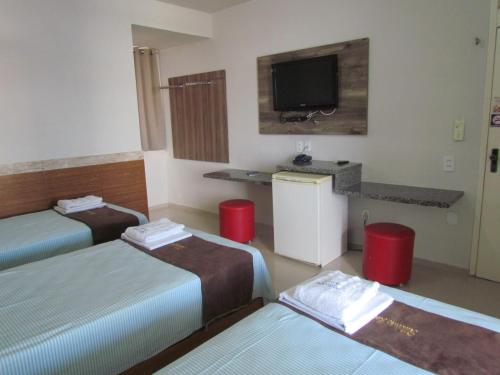 a hotel room with three beds and a flat screen tv at Ribeirao Hotel in Sousa