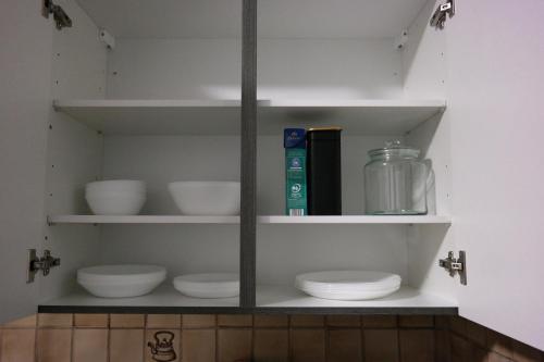 a shelf with white dishes and books in a kitchen at Ruhrpott Apartment Zentral Smart in Herne
