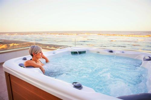 una mujer sentada en una bañera de hidromasaje con vistas al océano en You & Me Beach Hotel en Rímini