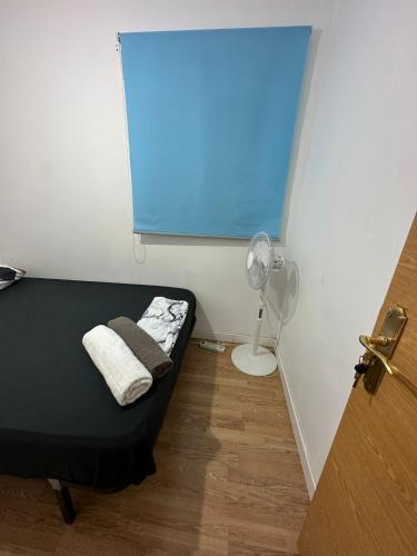 Habitación pequeña con cama y ventilador. en Fast Single Rooms en Madrid