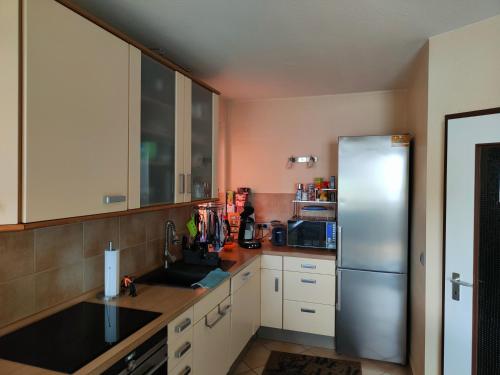 a kitchen with white cabinets and a stainless steel refrigerator at kleines Gästezimmer in Hannover