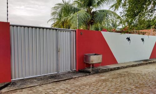 a red and white fence with a trash can next to it at Casa de Praia em Pirangi in Nísia Floresta