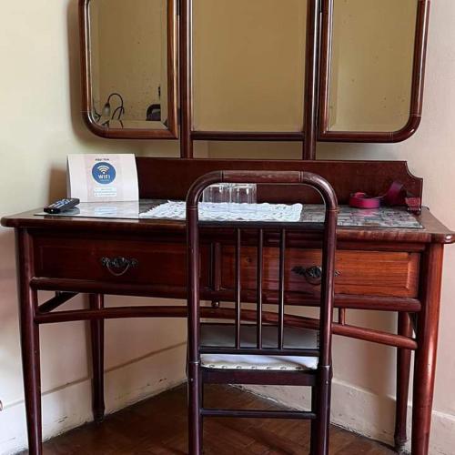 a wooden desk with a chair in front of a mirror at Hotel Bragança in Caxambu