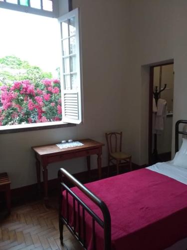 a bedroom with a bed and a window with a table at Hotel Bragança in Caxambu