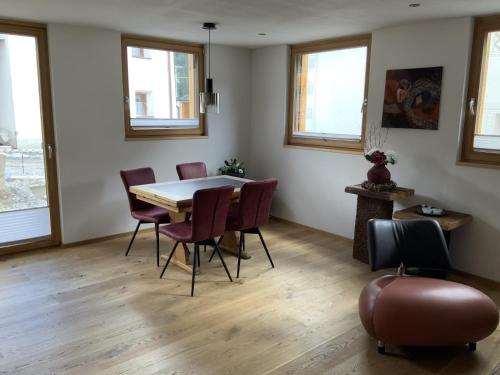 a dining room with a table and chairs and windows at Chasa Siringia EG in Samnaun - Laret