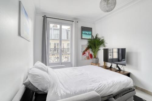 une chambre blanche avec un lit et une fenêtre dans l'établissement Grand Appart Spacieux Rénové Paris Métro Wifi, à Paris