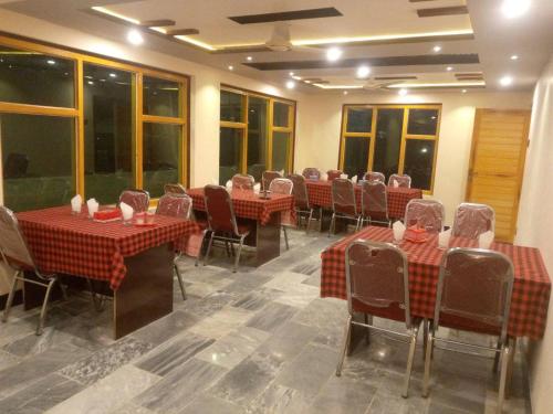 ein Esszimmer mit Tischen, Stühlen und Fenstern in der Unterkunft Shama Resort Hotel in Skardu