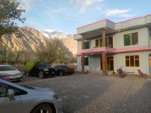 a house with cars parked in front of it with mountains at Shama Resort Hotel in Skardu