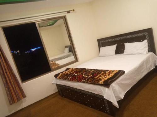a bedroom with a bed with a mirror and a window at Shama Resort Hotel in Skardu