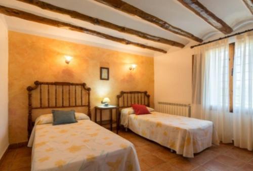 a bedroom with two beds in a room with a window at CASA RÚSTICA EN MAS ENFABONA in Els Ibarsos