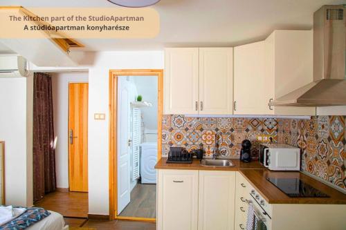 a kitchen with white cabinets and a sink at Tulip Home Guest House in Vác