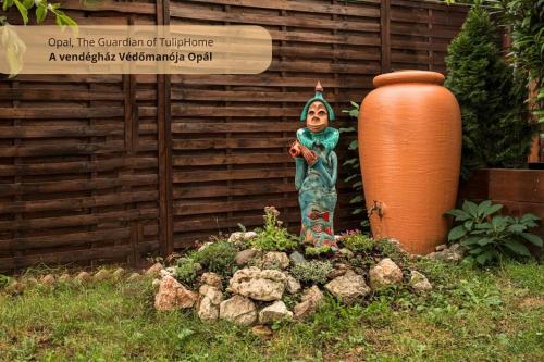 Una statua di una donna in un giardino vicino a un vaso. di Tulip Home Guest House a Vác