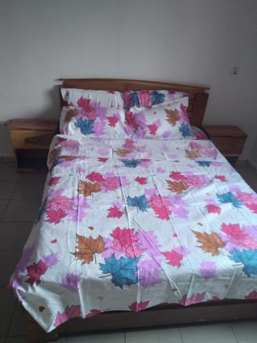 a bed with a floral comforter in a bedroom at The furnished residences of Fasso Kanu -villa in Bamako