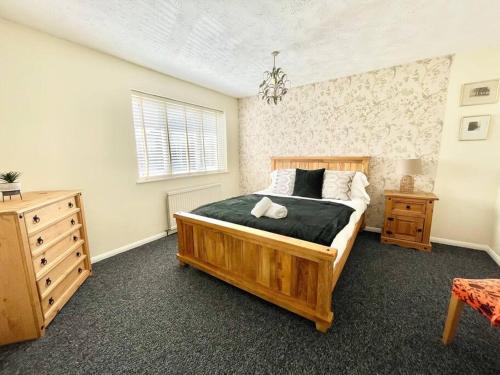 a bedroom with a wooden bed and a dresser at Ashford 3 Bedroom house with parking central area, private garden in Kent