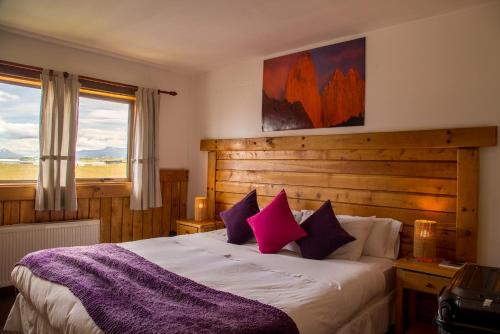 a bedroom with a large bed with purple pillows at Weskar Lodge Hotel in Puerto Natales