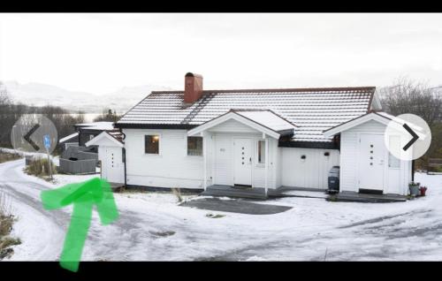 una casa en la nieve con una flecha verde en Lovely one bedroom apartment, en Tromsø