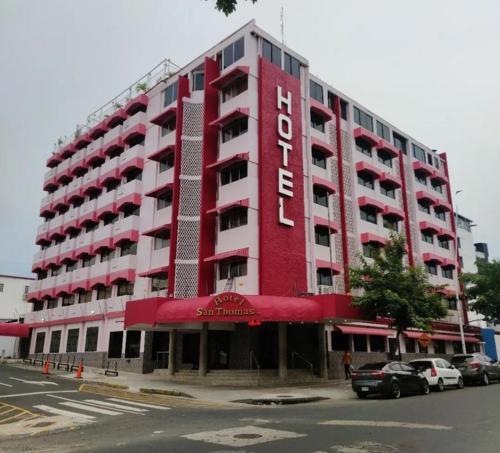 ein rotweißes Gebäude mit davor geparkt in der Unterkunft HOTEL SAN THOMAS INN in Panama-Stadt