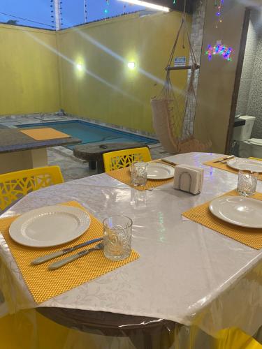 a table with white plates and yellow napkins on it at CASA ATALAIA 2 SUITES Salinopolis in Salinópolis