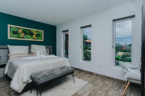 a bedroom with a bed and two windows at Hidden Villa Aruba in Oranjestad