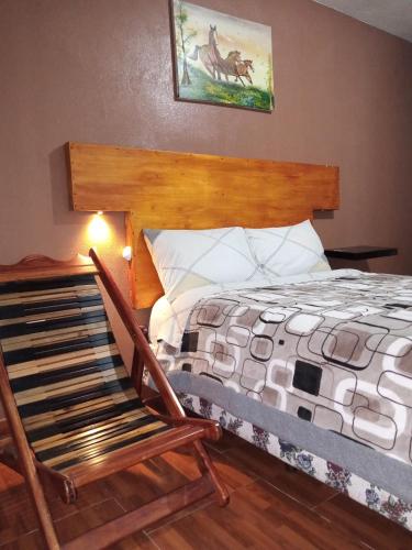 een slaapkamer met een bed en een schommelstoel bij Hostal Restaurante el Fogón Campero in Papallacta