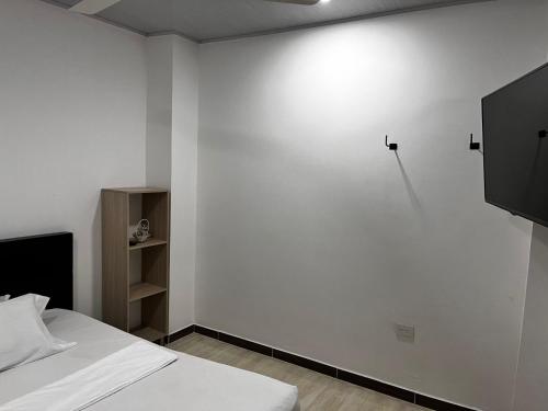 um quarto com uma cama e uma parede branca em EL EDÉN 102 em Puerto Triunfo