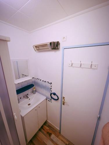 a white bathroom with a sink and a mirror at Studio vacances proche de la mer in Le Grau-du-Roi