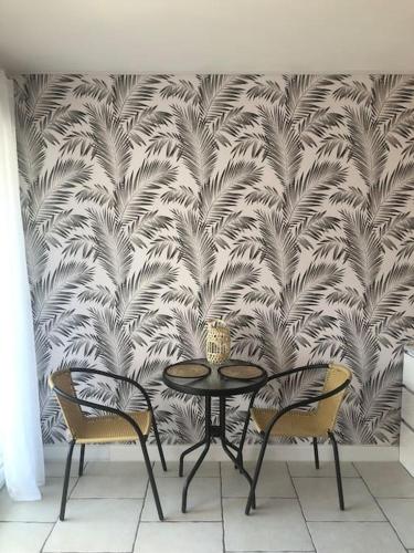 une table et deux chaises devant un mur dans l'établissement Le Drakkar - Studio chaleureux *Parking *CLIM *Wifi 2 pers., à La Grande Motte