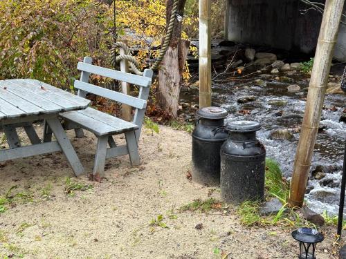a picnic table and two trash cans next to a bench at Escape to a Streamside Cabin in the Lower Catskills in Wurtsboro