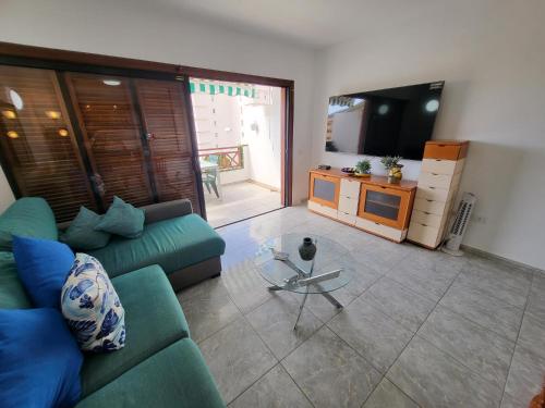 a living room with a green couch and a glass table at Victoria Court II in Los Cristianos