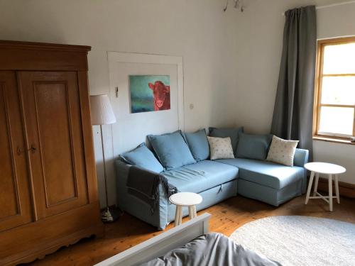 a living room with a blue couch and a window at Ferienwohnung im Edelhof in Neustadt am Rübenberge