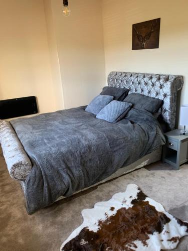 1 dormitorio con 1 cama grande con manta gris en Hays cottage en Halifax