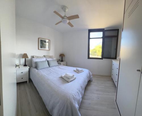 a white bedroom with a bed and a ceiling fan at Apartamento Bungamerica 2 bedrooms Costa Adeje in Playa de las Americas