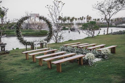a row of wooden benches in front of a lake at Rumah Luwih Bali in Keramas