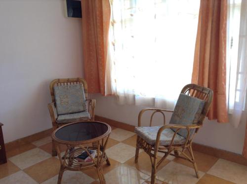 two chairs and a table in a room with a window at Ebrahim Flats - Grand Baie Beach in Grand Baie