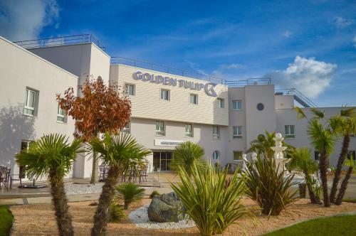 a building with palm trees in front of it at Golden Tulip Dieppe Hôtel & Spa in Saint-Aubin-sur-Scie