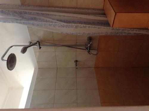 a shower in a bathroom with a tile floor at Ebrahim Flats - Grand Baie Beach in Grand Baie