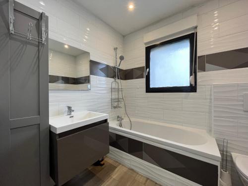 ein Badezimmer mit einem Waschbecken und einer Badewanne sowie einem TV in der Unterkunft Family Duplex 3BR au Coeur de Talange in Talange