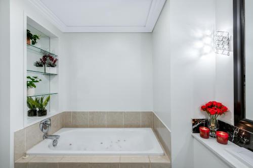 a large bath tub in a white bathroom with red candles at Your Next Viaduct Getaway! in Auckland
