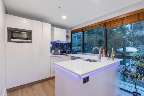 a kitchen with white cabinets and a large window at Your Next Viaduct Getaway! in Auckland