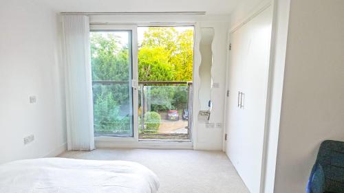 a bedroom with a bed and an open window at Modern Spacious 2-Bed Apartment in London in Bromley