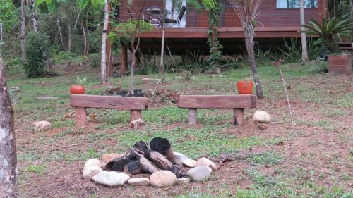two benches in a yard with a pile of logs at Cabanas sítio Ancestral in Morretes