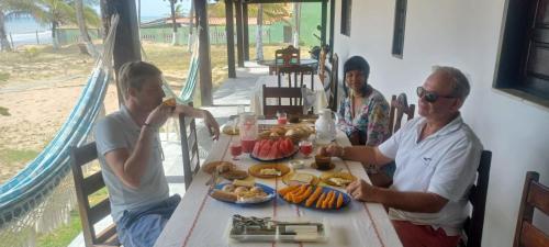 un grupo de personas sentadas en una mesa con comida en Pousada Marinheiro, en Sítio