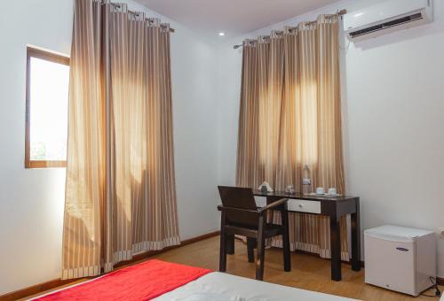 a bedroom with a desk with a chair and a window at Baig's Guest House in São Tomé