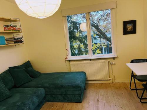 a living room with a green couch and a window at Nice two room flat 15 minutes from Stockholm C . in Huddinge