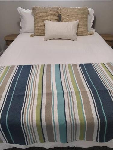 a striped bed with two pillows on top of it at Coastal Pod in Port Macquarie