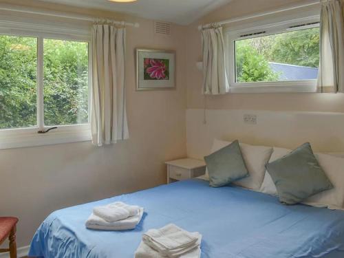 a bedroom with a blue bed with two towels on it at Satchwell Chalet on Reelig Estate near Inverness in Kirkhill